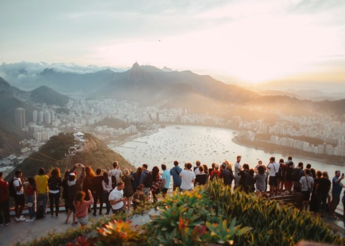 group of people standing facing lake view